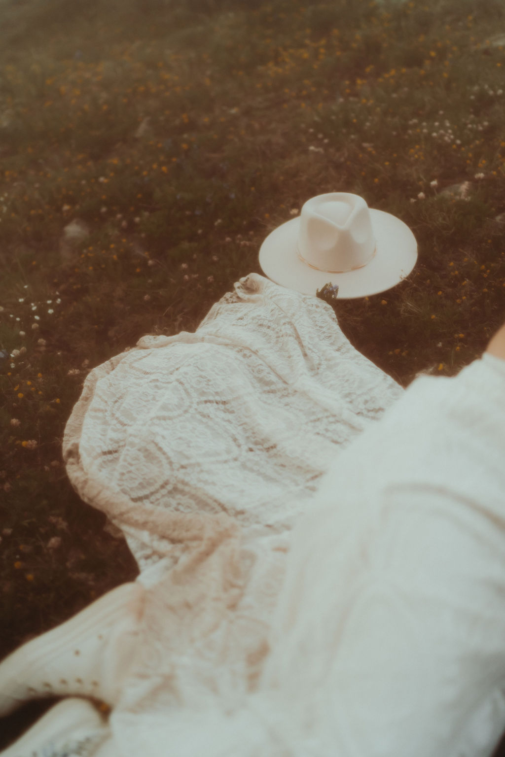 a photo of a beautiful wedding/elopement dress with some accessories in a beautiful green field with wildflowers