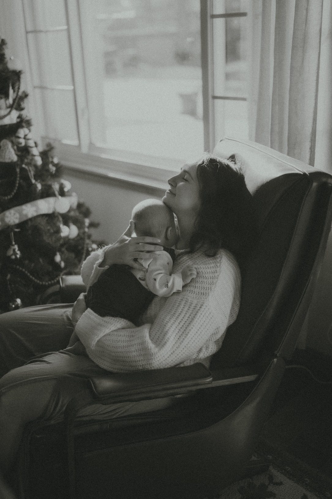 an intimate, in-home, family session as a mother hugs and cuddles her new born in a family photoshoot